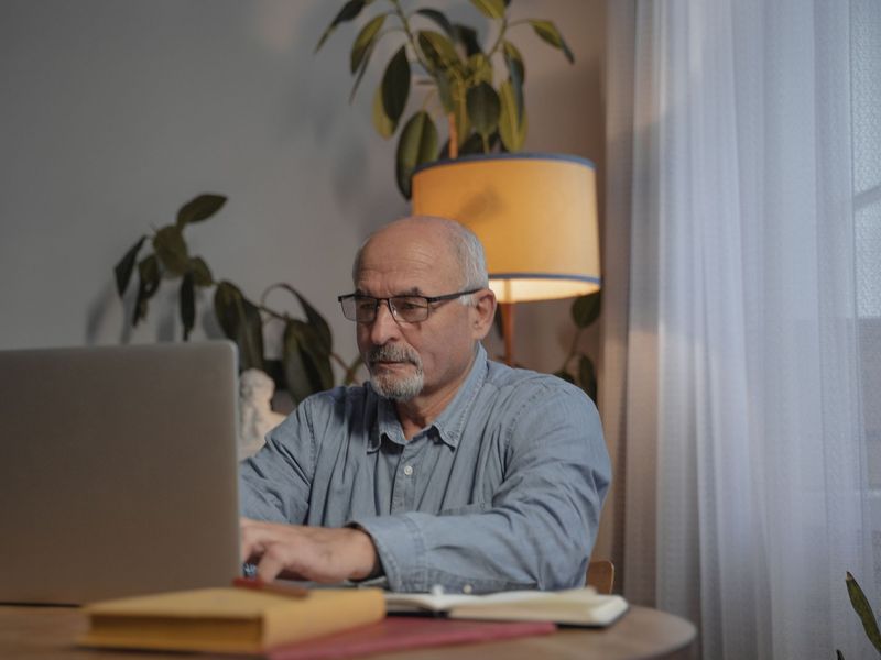 An older man working through an online course on a laptop at home
