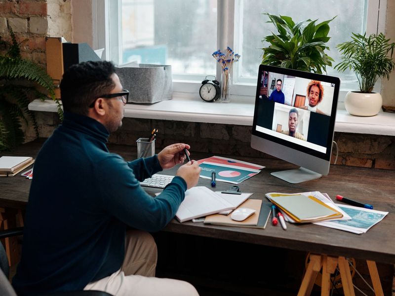 A man taking part in a live online class from his desk, with the trainer on screen